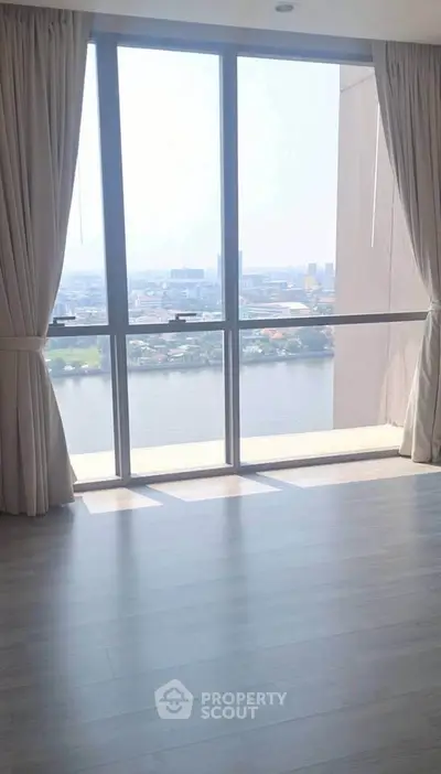 Spacious room with floor-to-ceiling windows offering stunning river view and abundant natural light.