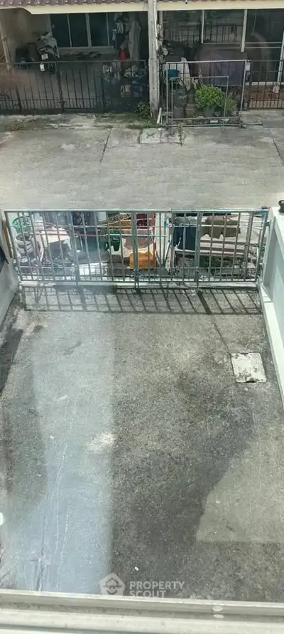 Urban balcony with concrete flooring and metal railing, overlooking a street view.