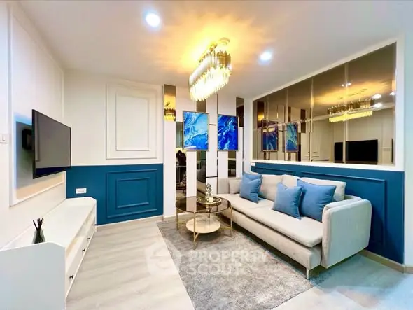 Modern living room with elegant decor, featuring a plush sofa, stylish chandelier, and vibrant artwork.