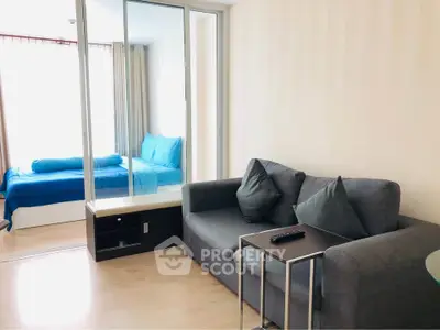 Modern living room with gray sofa and view into cozy bedroom with blue bedding