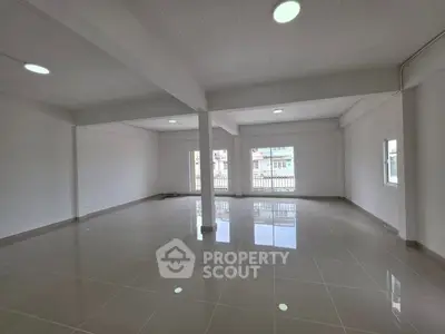 Spacious open-plan interior with large windows and glossy tiled flooring, ideal for versatile living or office space.