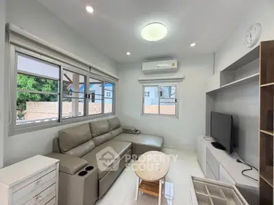 Modern living room with sleek furniture and large windows offering natural light.