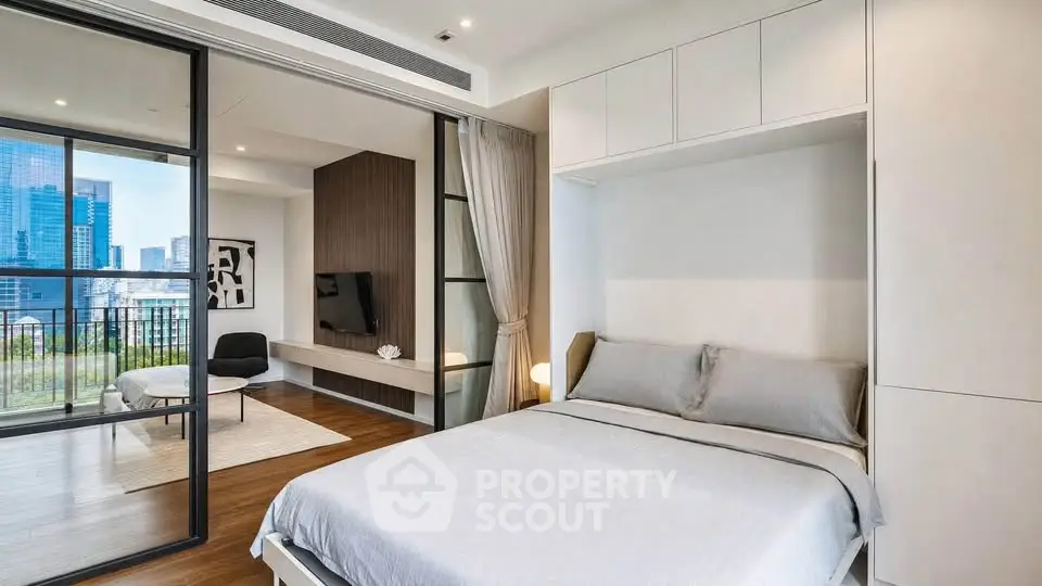 Modern bedroom with sliding glass doors leading to a spacious living area and city view balcony.