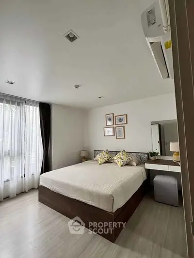 Spacious bedroom with modern decor and large window for natural light