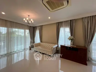 Elegant living room with chandelier, white sofa, and large windows with curtains.