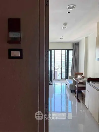 Modern apartment interior with open layout, sleek kitchen, and bright living area leading to a balcony with city views.