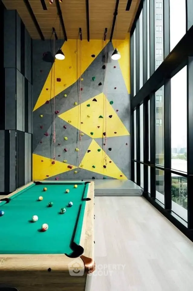 Modern recreational room with pool table and climbing wall in luxury building
