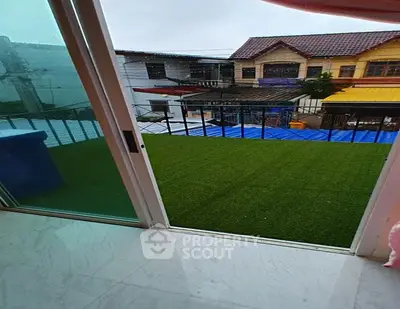 Charming balcony view with artificial grass overlooking neighboring houses.