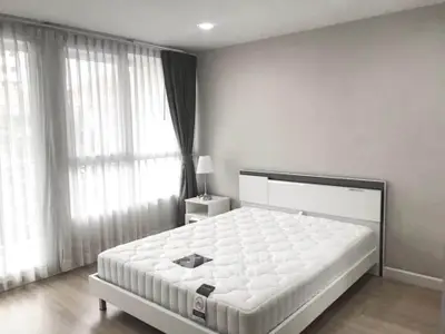 Spacious bedroom with large window and modern furnishings in a bright apartment.