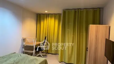 Cozy bedroom with green curtains, study desk, and wardrobe