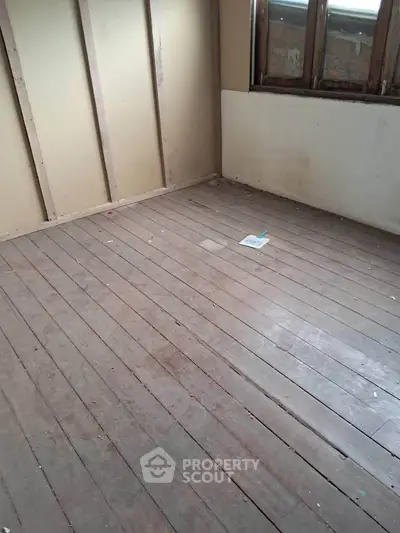 Unfinished room with wooden flooring and exposed walls, potential for renovation.