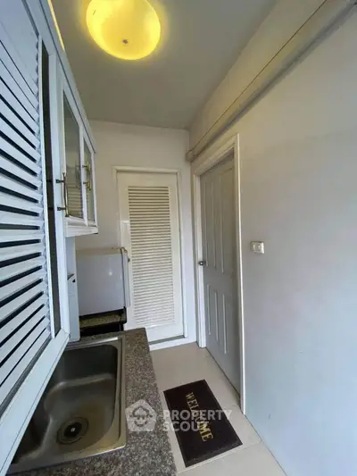 Compact kitchen with granite countertop and welcome mat in cozy apartment