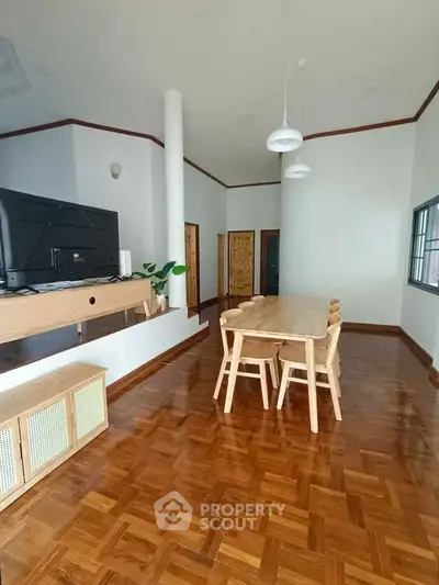 Spacious living room with wooden flooring and modern furniture, perfect for family gatherings.