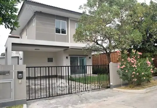 Modern two-story house with gated driveway and lush garden