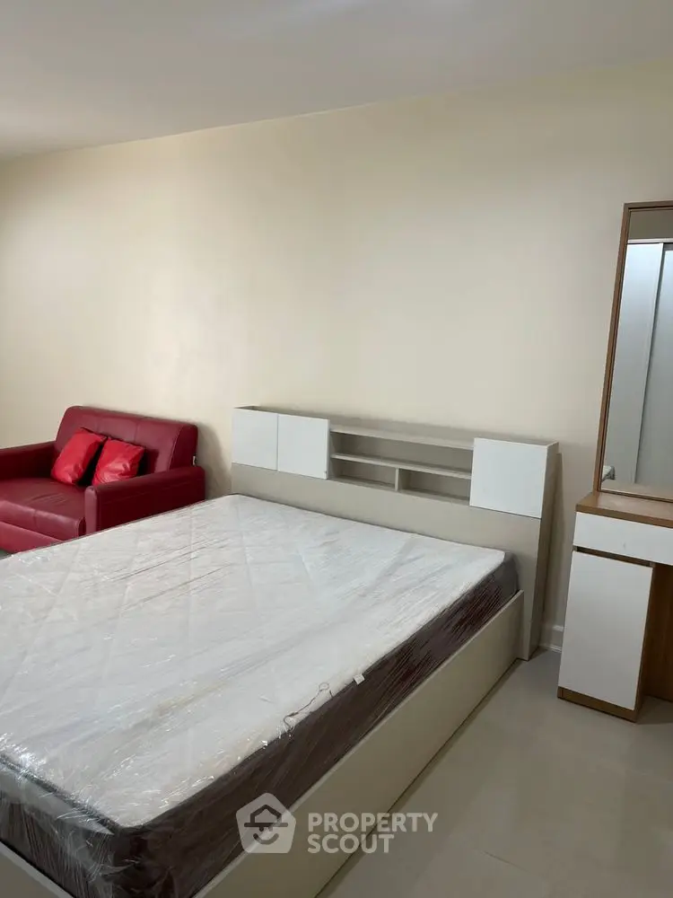 Spacious bedroom with modern furniture and red sofa, perfect for comfort and style.
