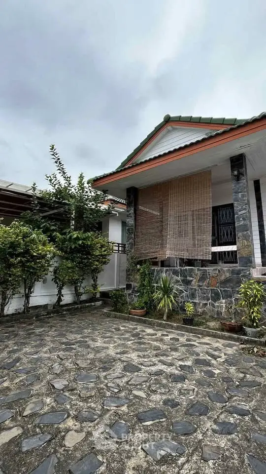 Charming single-story home with stone facade and lush greenery, perfect for serene living.