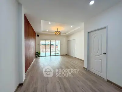 Spacious modern living room with wooden flooring and elegant lighting, featuring large sliding glass doors.