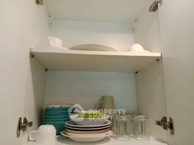 Spacious kitchen cabinet with neatly arranged dishes and glasses, showcasing ample storage space.