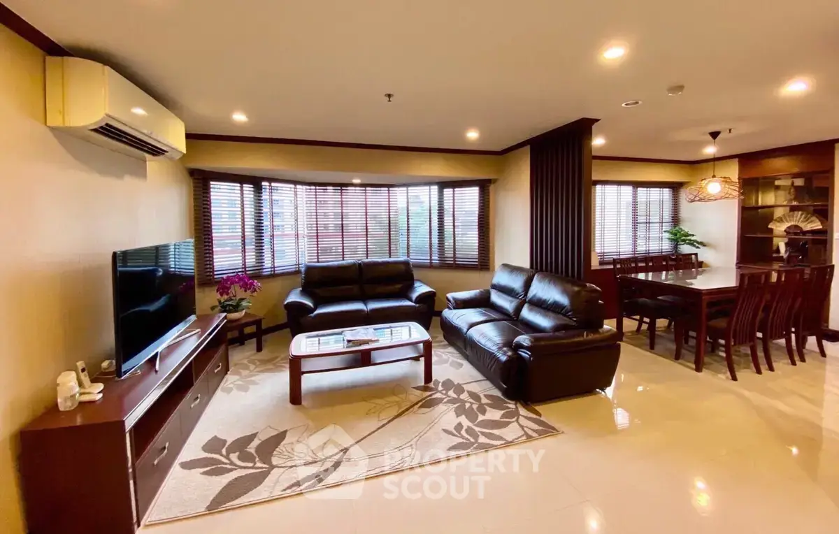 Spacious living room with elegant leather sofas and modern dining area in open layout.