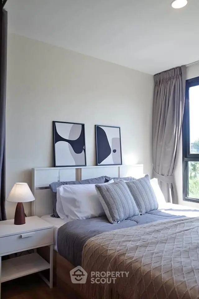 Cozy bedroom with modern decor and large window offering natural light.