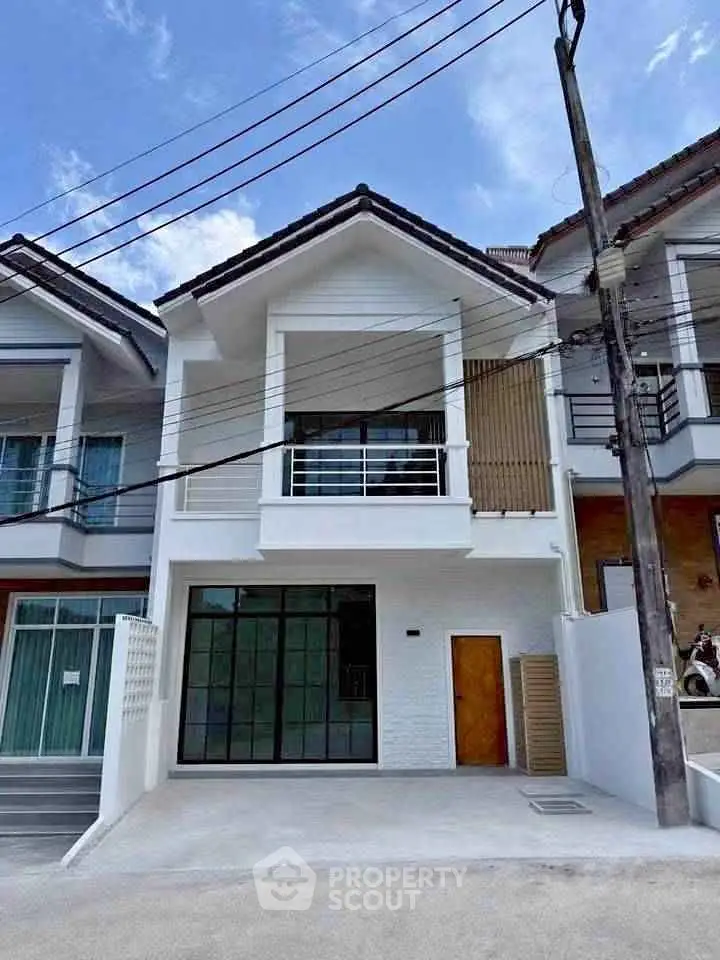 Modern two-story townhouse with balcony and large windows in a suburban neighborhood.