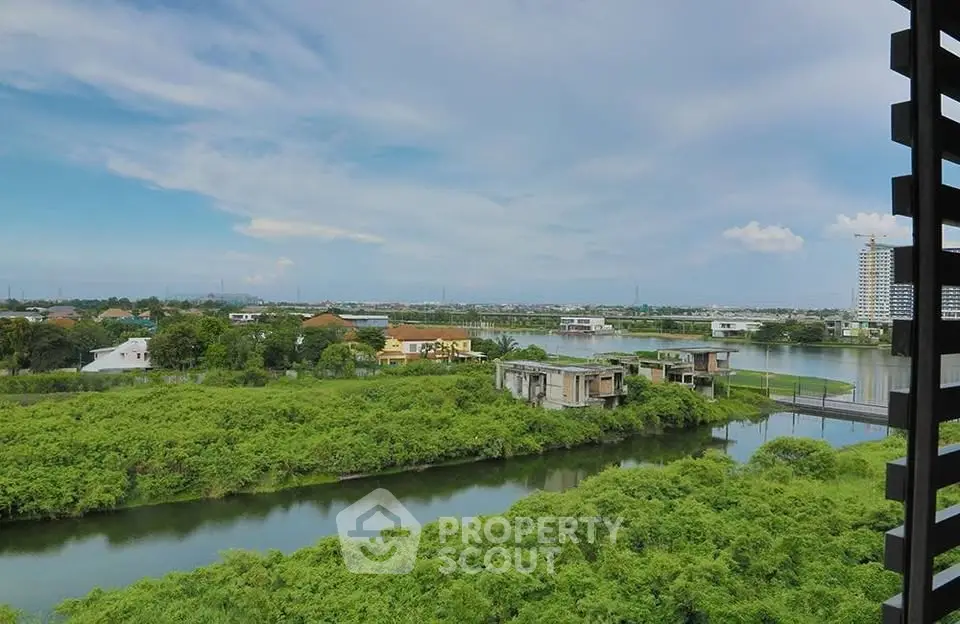 Stunning panoramic view of lush greenery and serene waterway from a high-rise balcony.