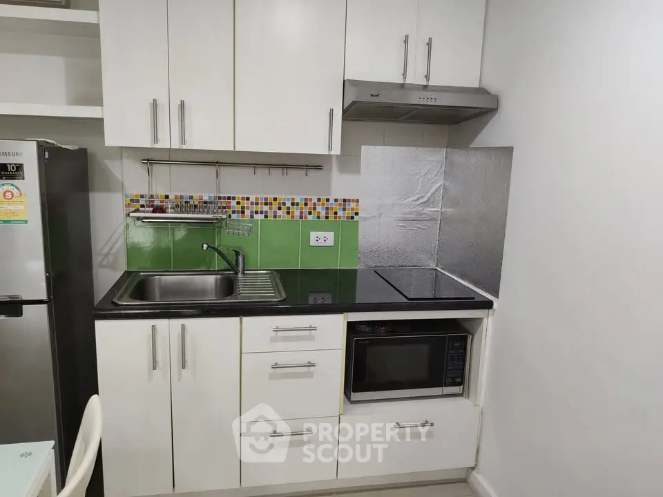Modern compact kitchen with sleek white cabinets and colorful backsplash