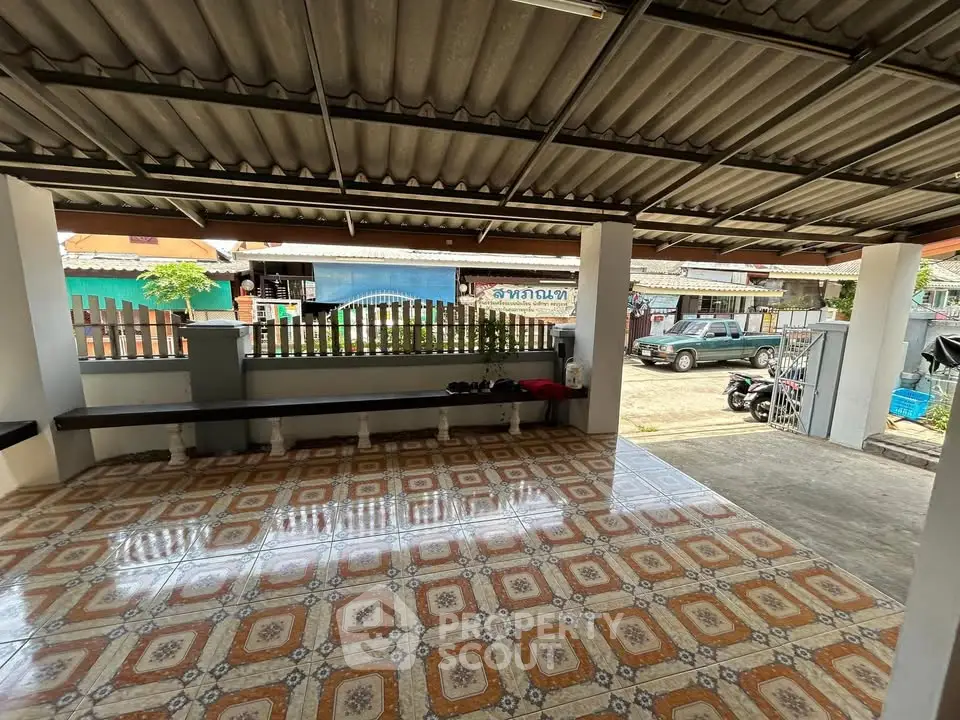 Spacious covered outdoor area with tiled flooring and street view, perfect for parking or gatherings.