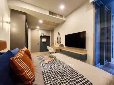 Modern bedroom with stylish decor, large TV, and cozy ambiance in a contemporary apartment.