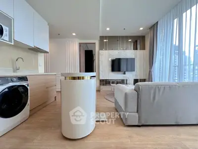 Modern open-plan living room with sleek kitchen and city view, featuring stylish furniture and appliances.