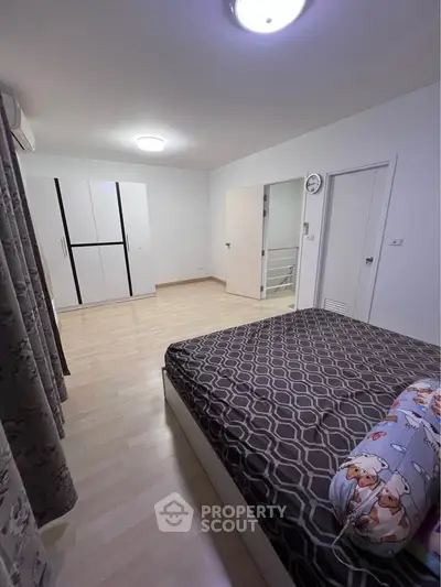 Spacious bedroom with modern decor and ample natural light, featuring a stylish bed and wardrobe.