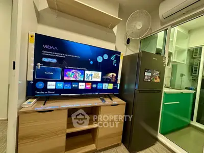 Modern living room with smart TV, fridge, and air conditioning in a cozy apartment.