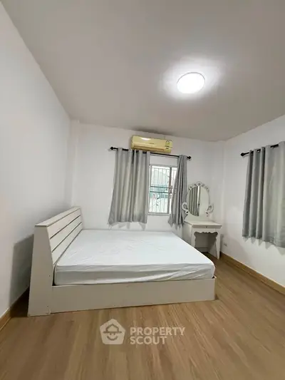 Spacious bedroom with modern furnishings and natural light, featuring a comfortable bed and stylish vanity.