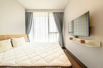 Modern bedroom with large window and wall-mounted TV, featuring elegant curtains and a comfortable bed.