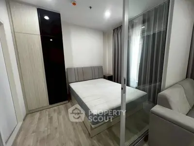 Modern bedroom with glass partition and sleek furnishings in a stylish apartment.