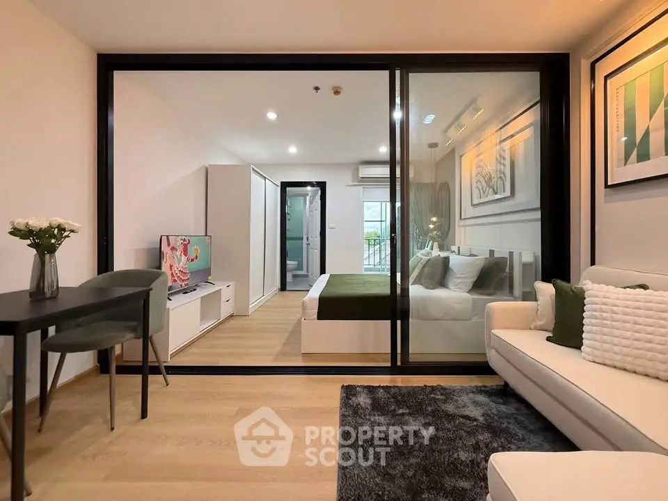 Modern studio apartment with glass partition, stylish decor, and cozy ambiance.