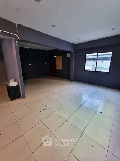 Spacious unfurnished room with large window and tiled flooring, ideal for customization.