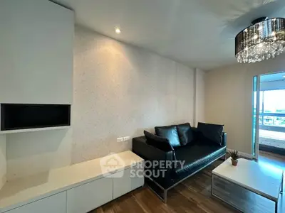 Modern living room with sleek black sofa and elegant chandelier in stylish apartment.
