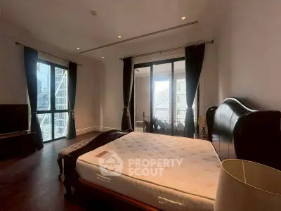 Luxurious bedroom with city view and elegant furnishings in high-rise apartment.