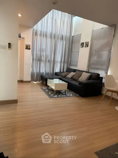 Spacious living room with high ceilings and modern decor in a stylish apartment.
