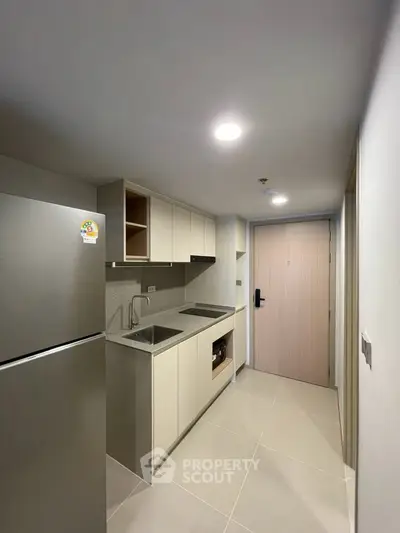 Modern compact kitchen with sleek cabinetry and stainless steel appliances in a contemporary apartment.
