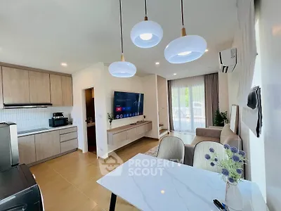 Modern open-plan living room with stylish kitchen and elegant dining area, featuring contemporary lighting and decor.