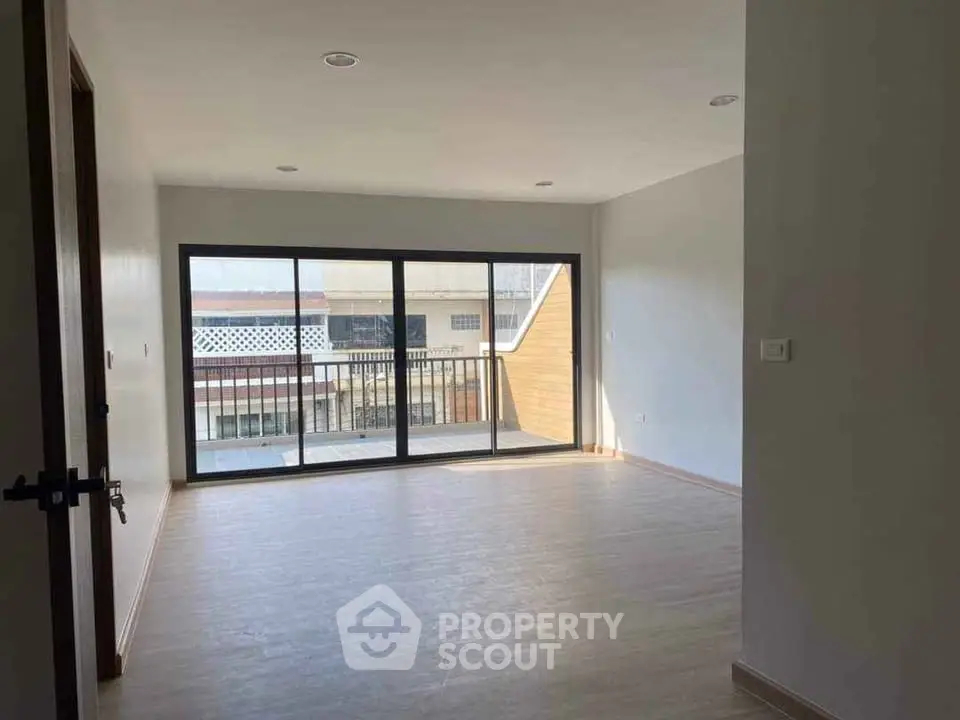 Spacious empty living room with large windows and balcony access in modern apartment.