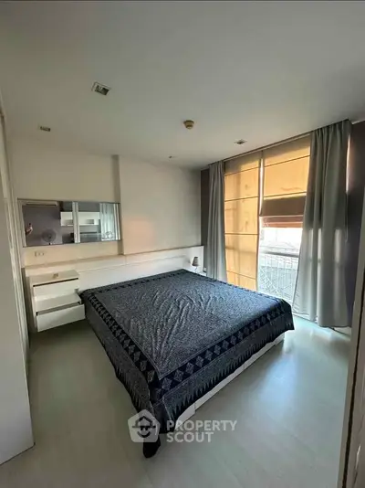 Spacious bedroom with large windows and modern decor in a stylish apartment.