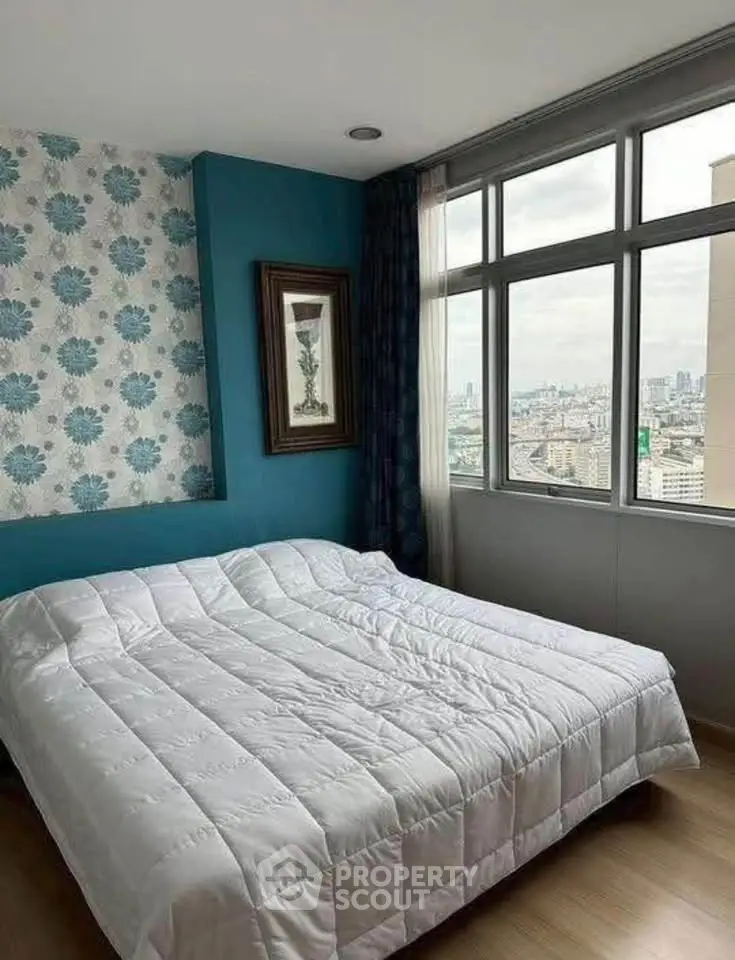 Cozy bedroom with city view, featuring large windows and stylish decor.