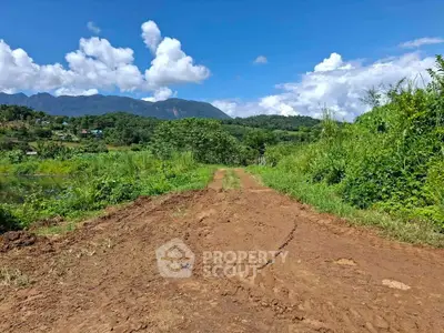Scenic rural land with lush greenery and mountain views, perfect for development or agriculture.