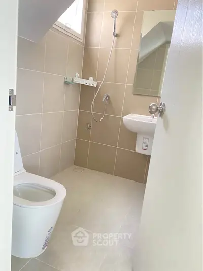 Modern bathroom with sleek fixtures and neutral tiles, featuring a compact design ideal for urban living.