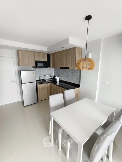 Modern kitchen with dining area featuring sleek cabinetry and contemporary lighting in a stylish apartment.