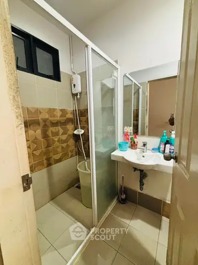 Compact bathroom with shower and sink, featuring modern tiles and essential toiletries.