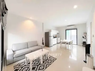 Spacious modern living room with open kitchen and dining area, featuring sleek furniture and bright lighting.